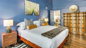 Un dormitorio con cama, mesitas de noche, cómoda y obras de arte en las paredes.