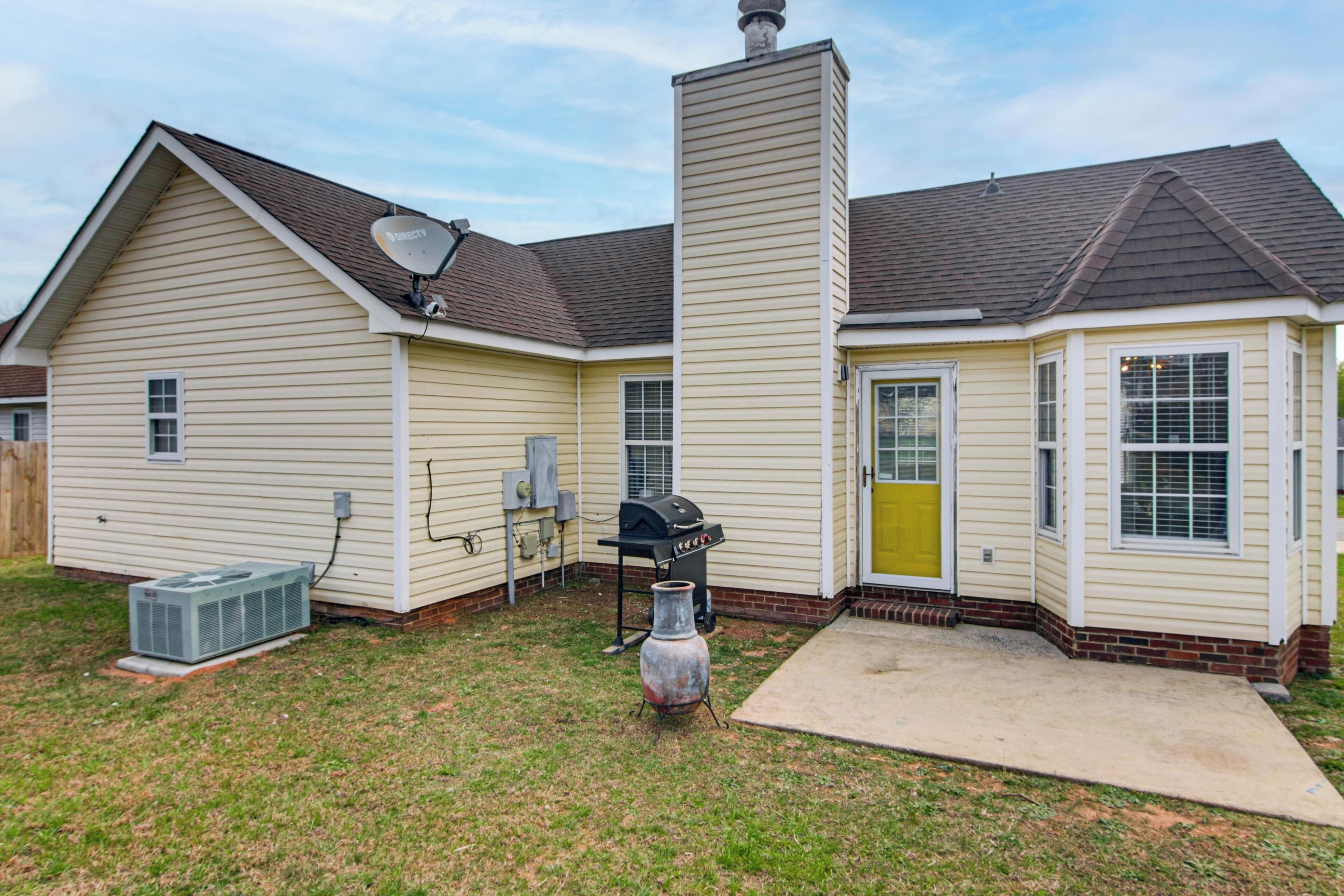A residential house with a chimney, satellite dish, and a grill in the backyard.