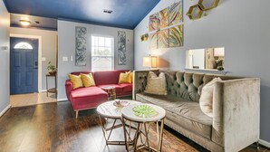 Una sala de estar con un sofá rojo, un sofá color beige, dos mesas redondas pequeñas y un techo azul.