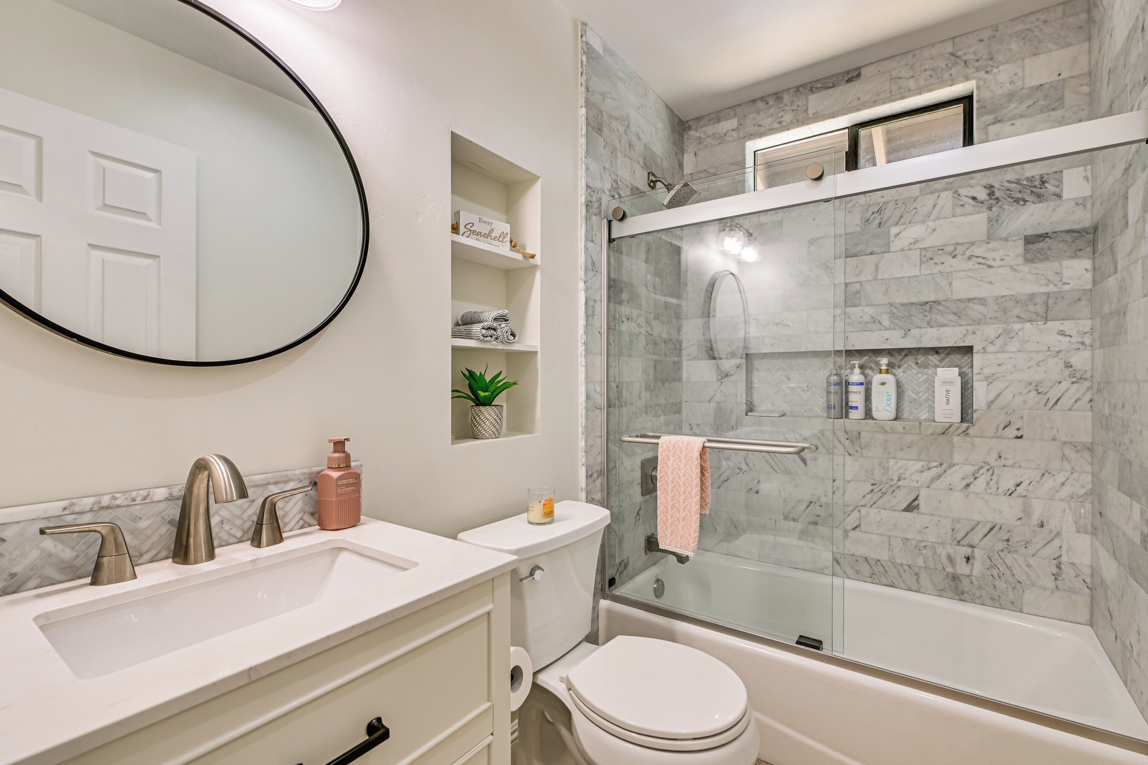 A modern bathroom with a glass-enclosed shower, a white sink, and a toilet.