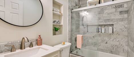 A modern bathroom with a glass-enclosed shower, a white sink, and a toilet.