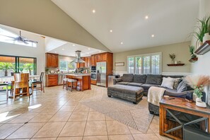 A spacious living area with a kitchen, dining area, and a large window providing natural light. - Walk to Lagoon! Luxe Coastal Escape w/ Pool Table (Carlsbad)