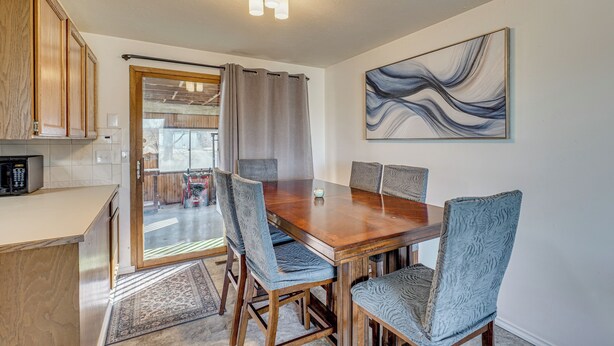 A dining area with a wooden table and chairs, a kitchen with wooden cabinets, and a large abstract painting on the wall. - Nurse-friendly Spokane Home Near Medical Centers (Spokane)