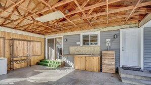 A covered outdoor area with a concrete floor, wooden benches, a small table, and a door. - Nurse-friendly Spokane Home Near Medical Centers (Spokane)
