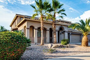 A two-story house with a tiled roof, arched columns, and a gravel driveway. - Swim-up Bar & Games! Ultimate Goodyear Group Stay (Goodyear)