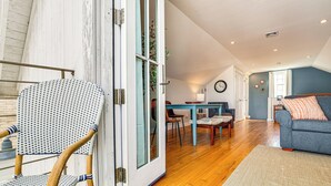 Une pièce avec un plancher en bois, un canapé bleu, une table à manger avec des chaises et une grande fenêtre.