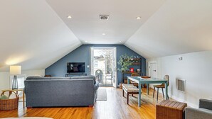 Un appartement de style « loft » avec un plafond haut, un coin repas, un salon avec un canapé et un téléviseur.