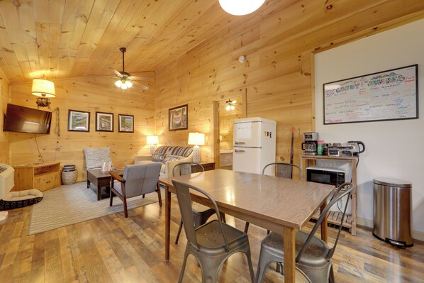 L’intérieur d’un chalet en bois comprend un coin repas, une cuisine et un mur sur lequel est affichée une liste écrite à la main.