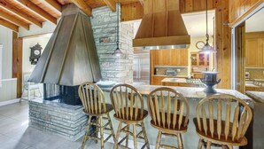 A kitchen with a stone fireplace, wooden chairs, and a large island. - Private Pool & Dock: Riverfront 'bridge Escape' (North Fort Myers)