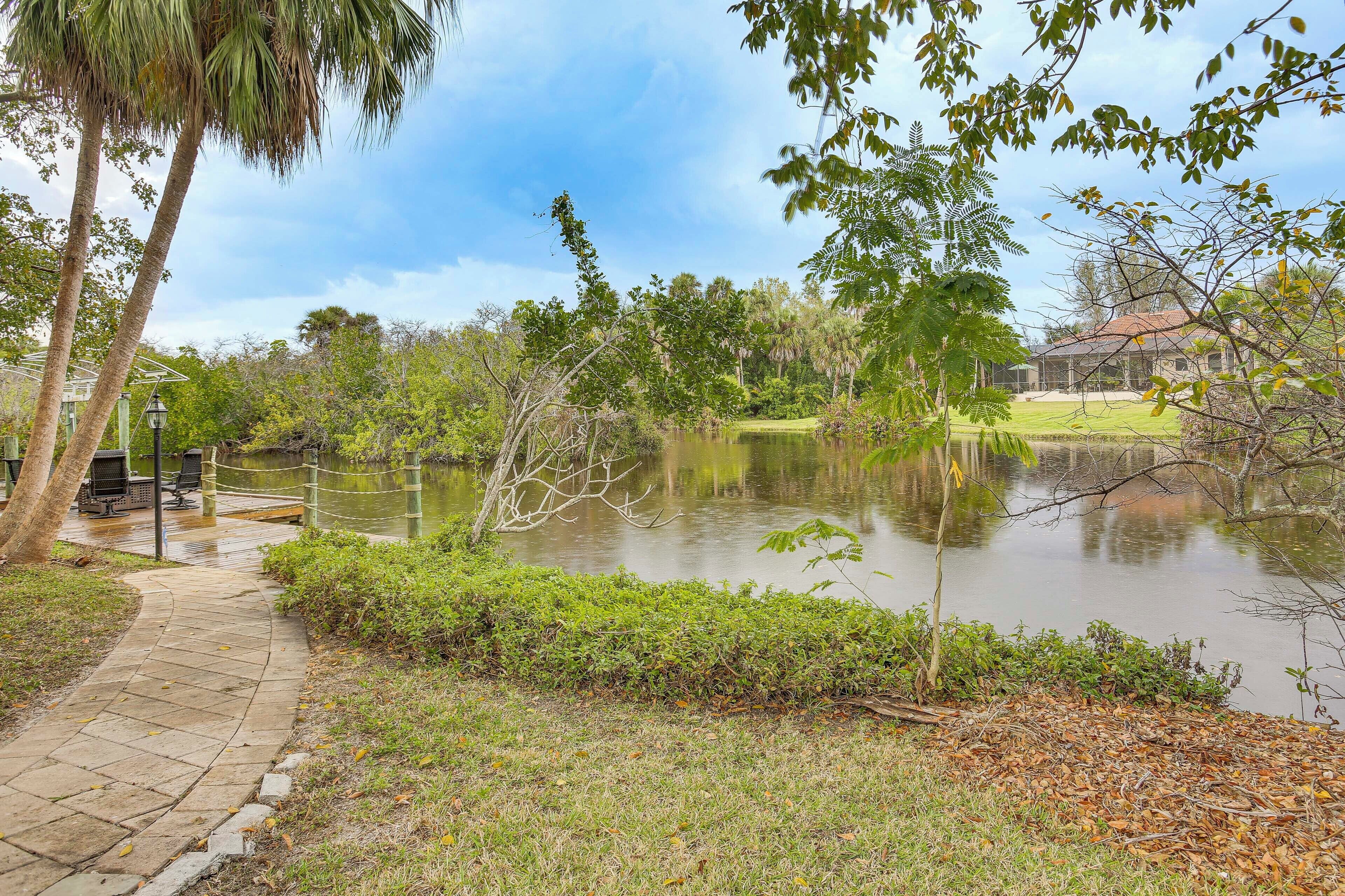 A pathway leading to a body of water with trees and a building in the background.