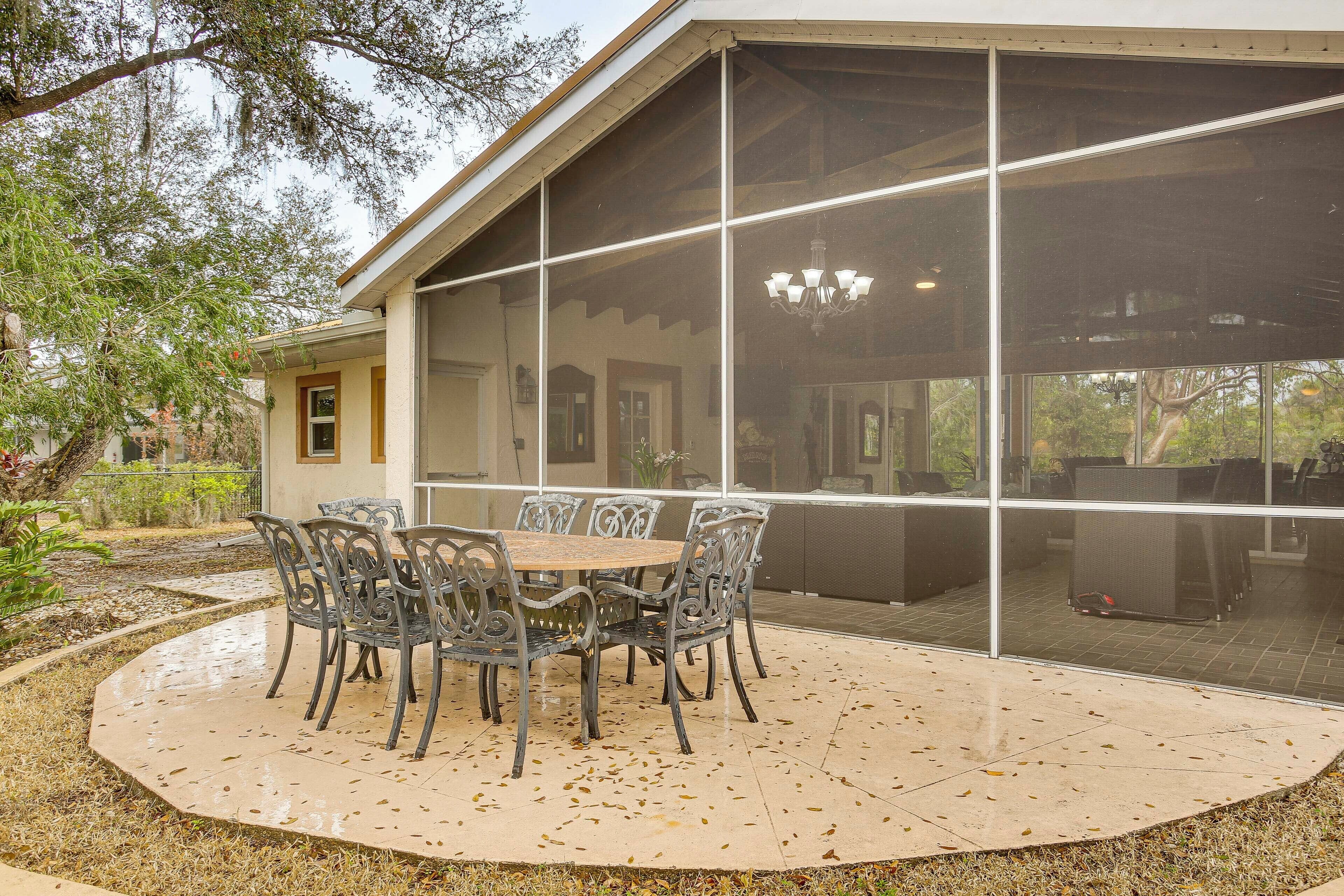 Un porche cubierto con una mesa, sillas y un cerramiento de vidrio, con vistas al exterior.