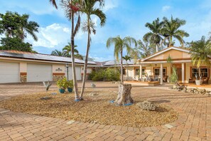 A residential property with a paved courtyard, palm trees, and a garage. - Private Pool & Dock: Riverfront 'bridge Escape' (North Fort Myers)