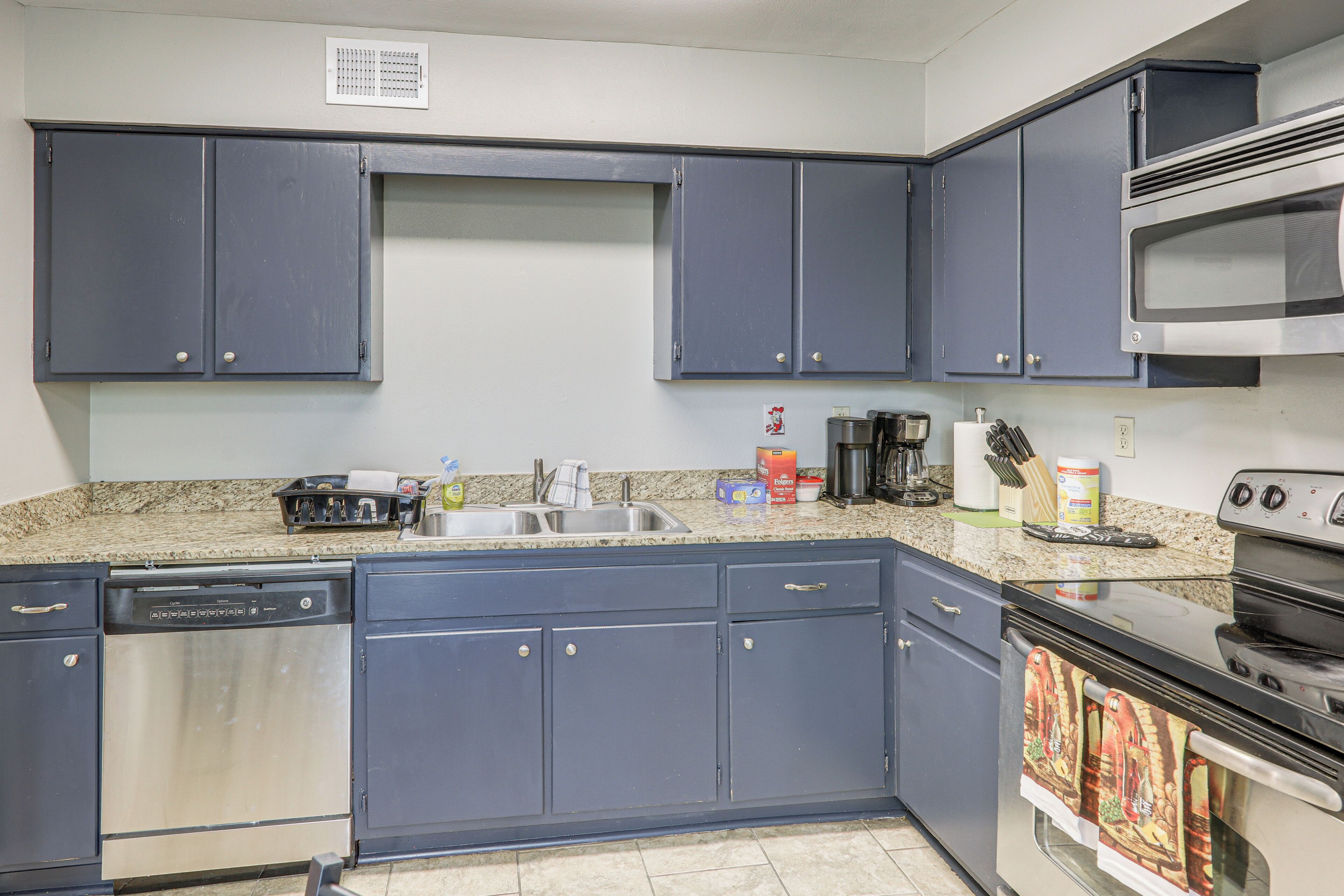 A kitchen with blue cabinets, a dishwasher, a stove, and a microwave.
