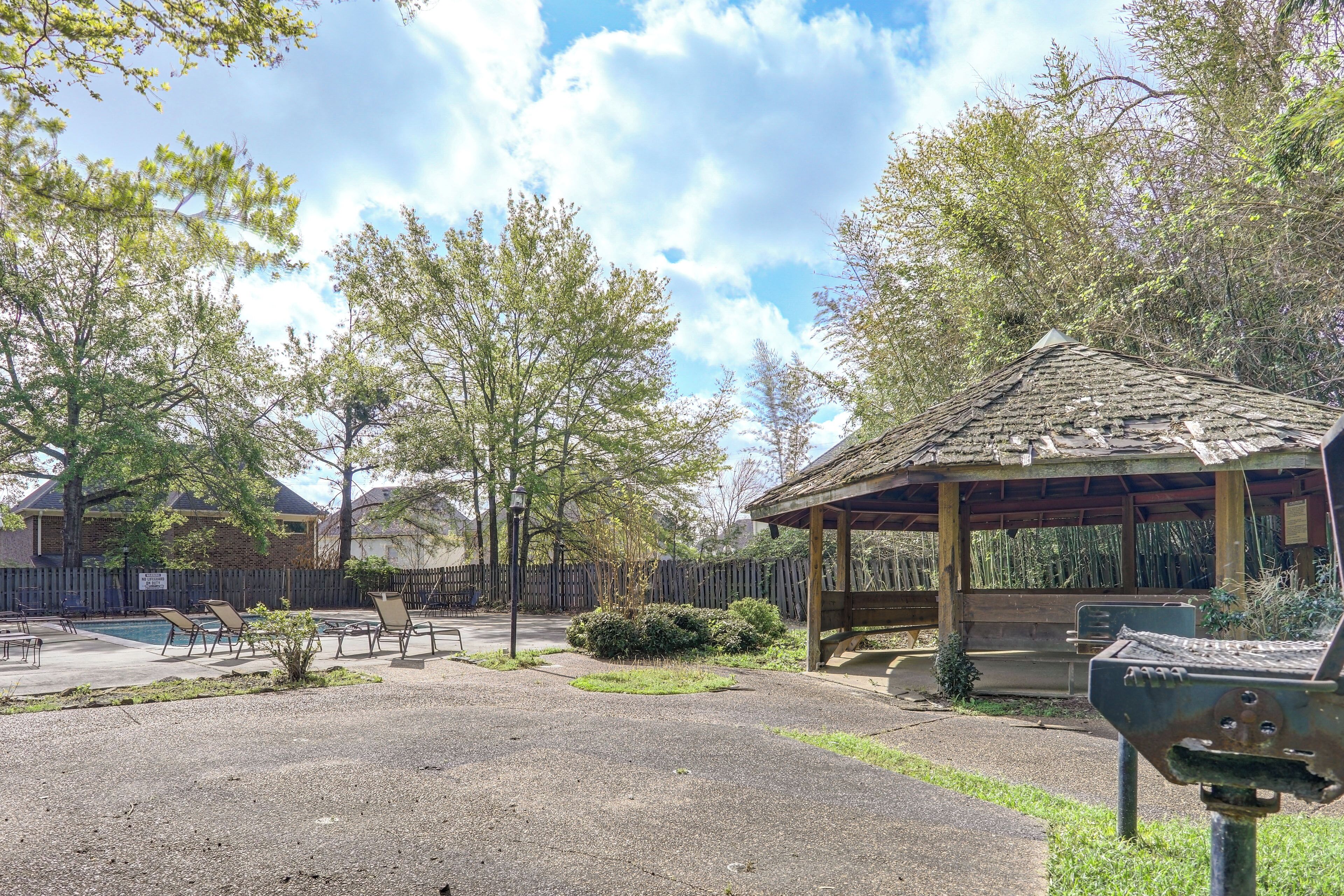 Ein überdachter Pavillon, ein Schwimmbad und ein eingezäunter Bereich mit Liegestühlen.