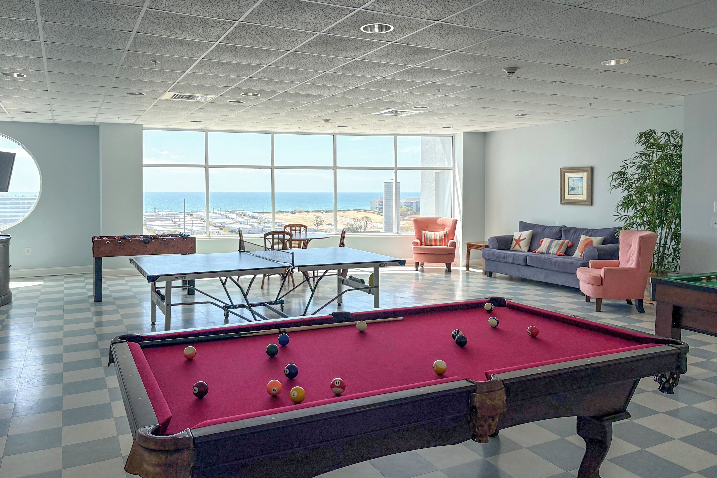 A pool table, a sofa, and a view of the ocean.