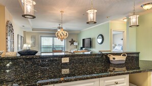 A kitchen with granite countertops, white cabinetry, and pendant lighting. - Walk to Ocean! Atlantic Beach Condo w/ Pool Access (Atlantic Beach)
