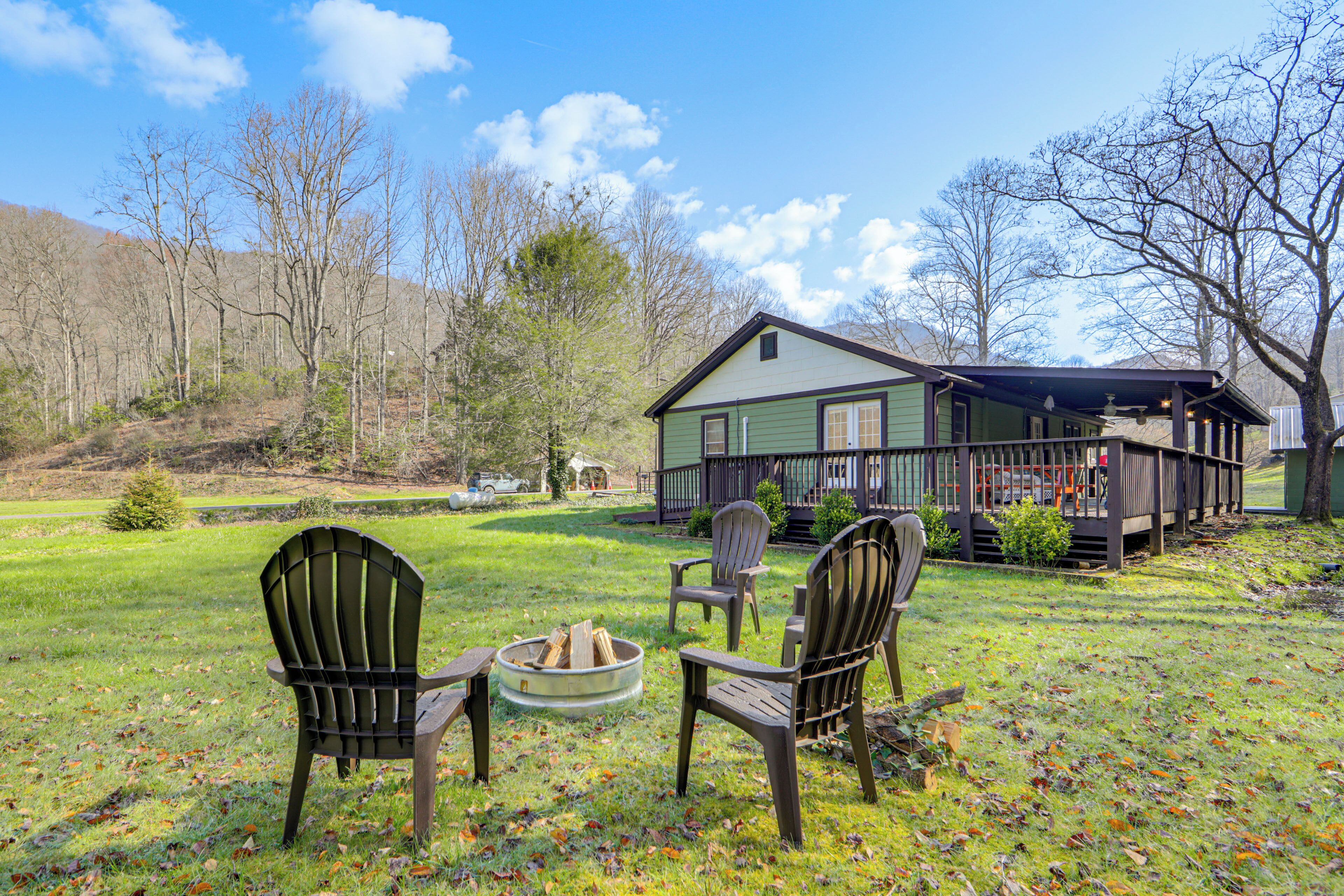 A house with a porch, two Adirondack chairs, and a fire pit in the yard.