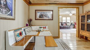 Un coin repas avec un banc en bois, une table blanche et un tableau encadré accroché au mur.