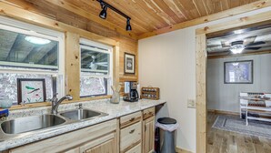 Une cuisine avec des meubles en bois, un évier à deux bacs et une poubelle.