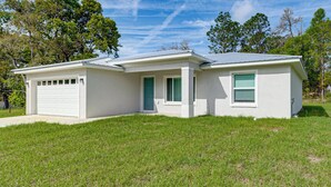 A single-story house with a garage, a front door, and a small porch. - Dunnellon Escape w/ Yard: 8 Mi to Rainbow River (Dunnellon)