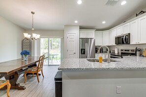 A modern kitchen with white cabinets, stainless steel appliances, and a granite countertop. - Dunnellon Escape w/ Yard: 8 Mi to Rainbow River (Dunnellon)