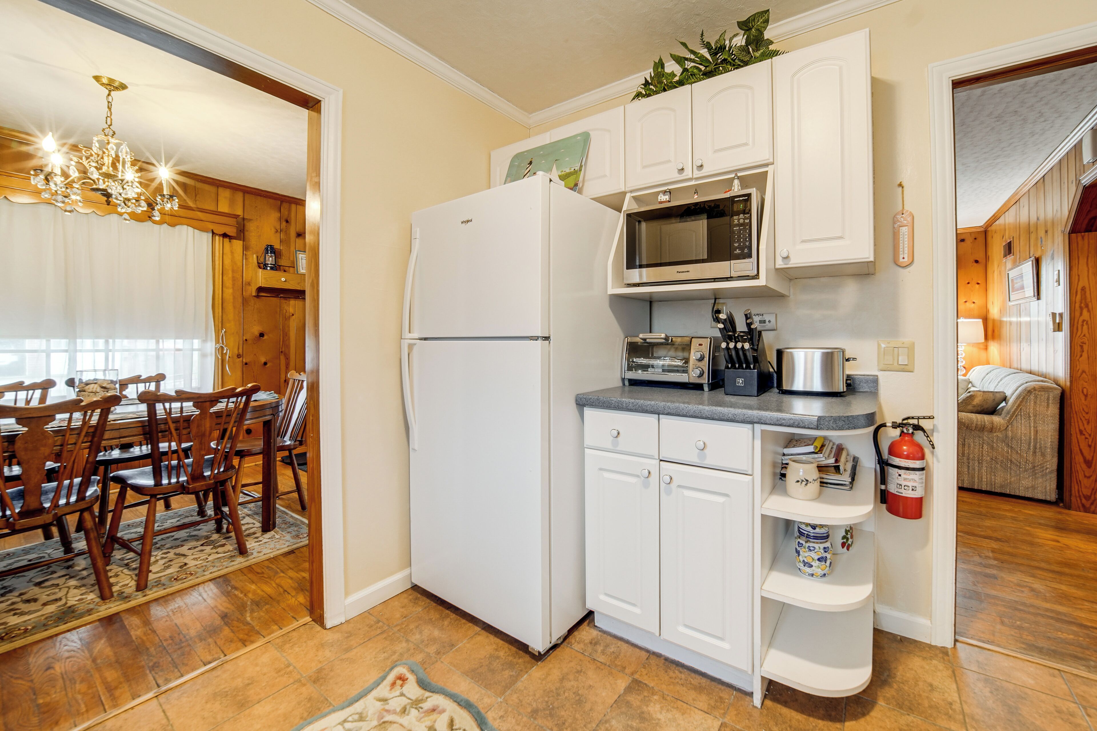 Una cocina compacta con armarios blancos, un refrigerador, un microondas y un tostador.