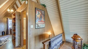 Un intérieur en bois avec une affiche, un escalier et un chapeau décoratif posé sur un présentoir.
