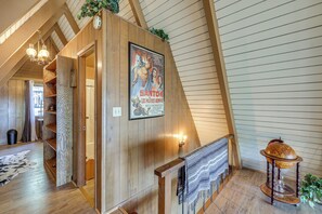 A wooden interior with a poster, a staircase, and a decorative hat on a stand. - Running Springs Retreat: Ski, Hike & Relax! (Running Springs)