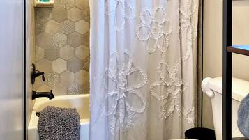 A bathroom with a bathtub, a toilet, and a shower curtain with floral patterns.