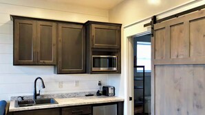 Una cocina con armarios de madera oscura, un microondas de acero inoxidable y un horno empotrado.