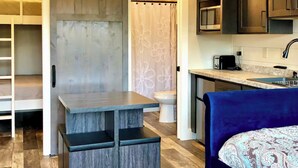 Una cocina compacta con microondas integrado, un lavamanos y un pequeño comedor.