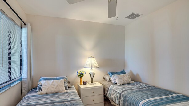 A bedroom with two beds, a nightstand with a lamp, and a window with blinds. - Resort-style Fort Myers Gem: Swim, Golf & Cruise! (Fort Myers)