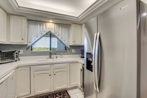 A kitchen with white cabinets, a stainless steel refrigerator, a built-in oven, and a window with a valance. - Resort-style Fort Myers Gem: Swim, Golf & Cruise! (Fort Myers)