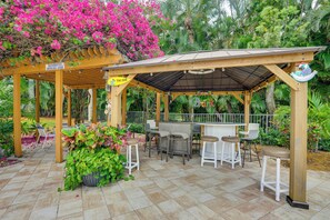A covered outdoor seating area with a bar, chairs, and a sign indicating a designated smoking area. - Resort-style Fort Myers Gem: Swim, Golf & Cruise! (Fort Myers)