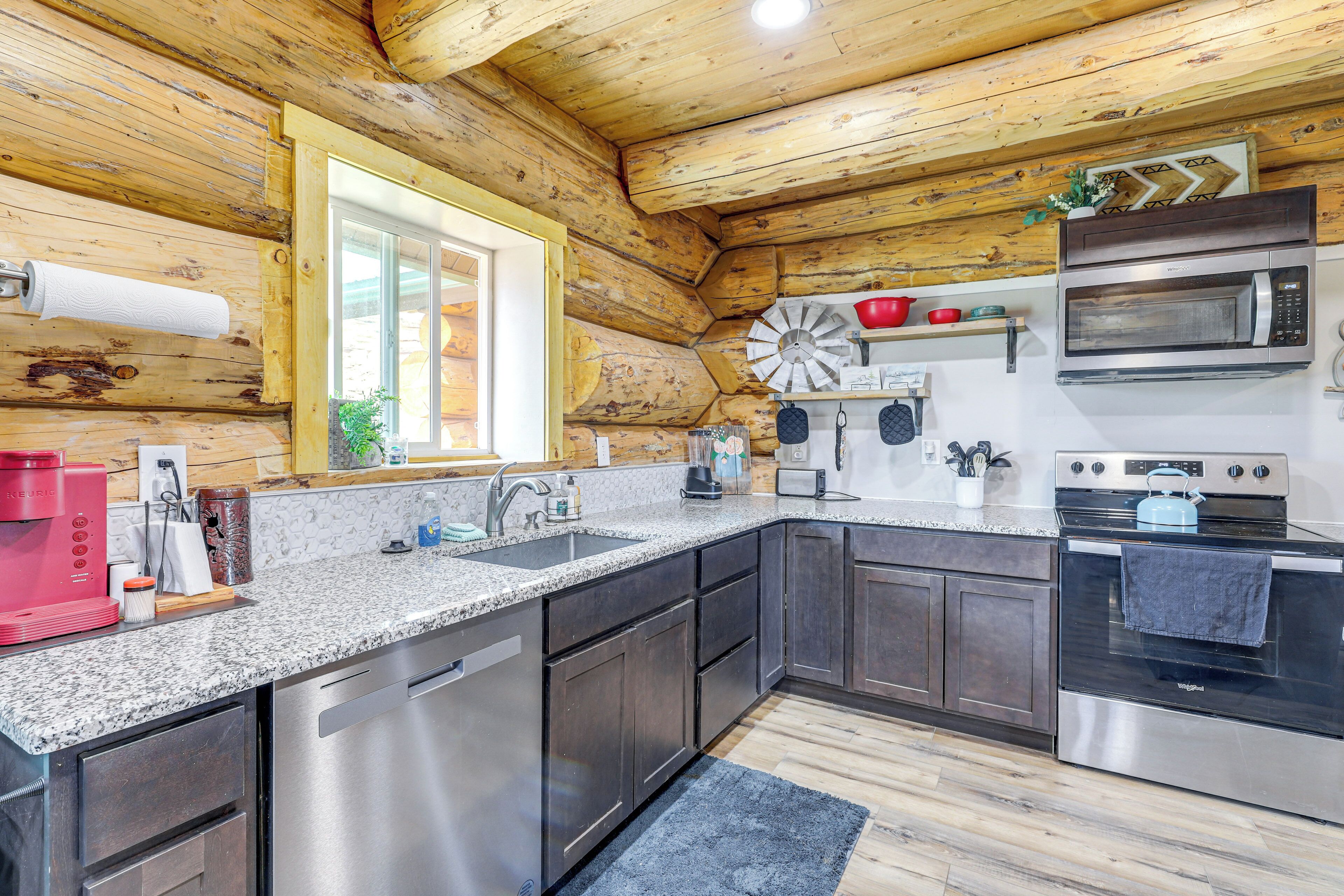 A modern kitchen with granite countertops, stainless steel appliances, and wooden walls.