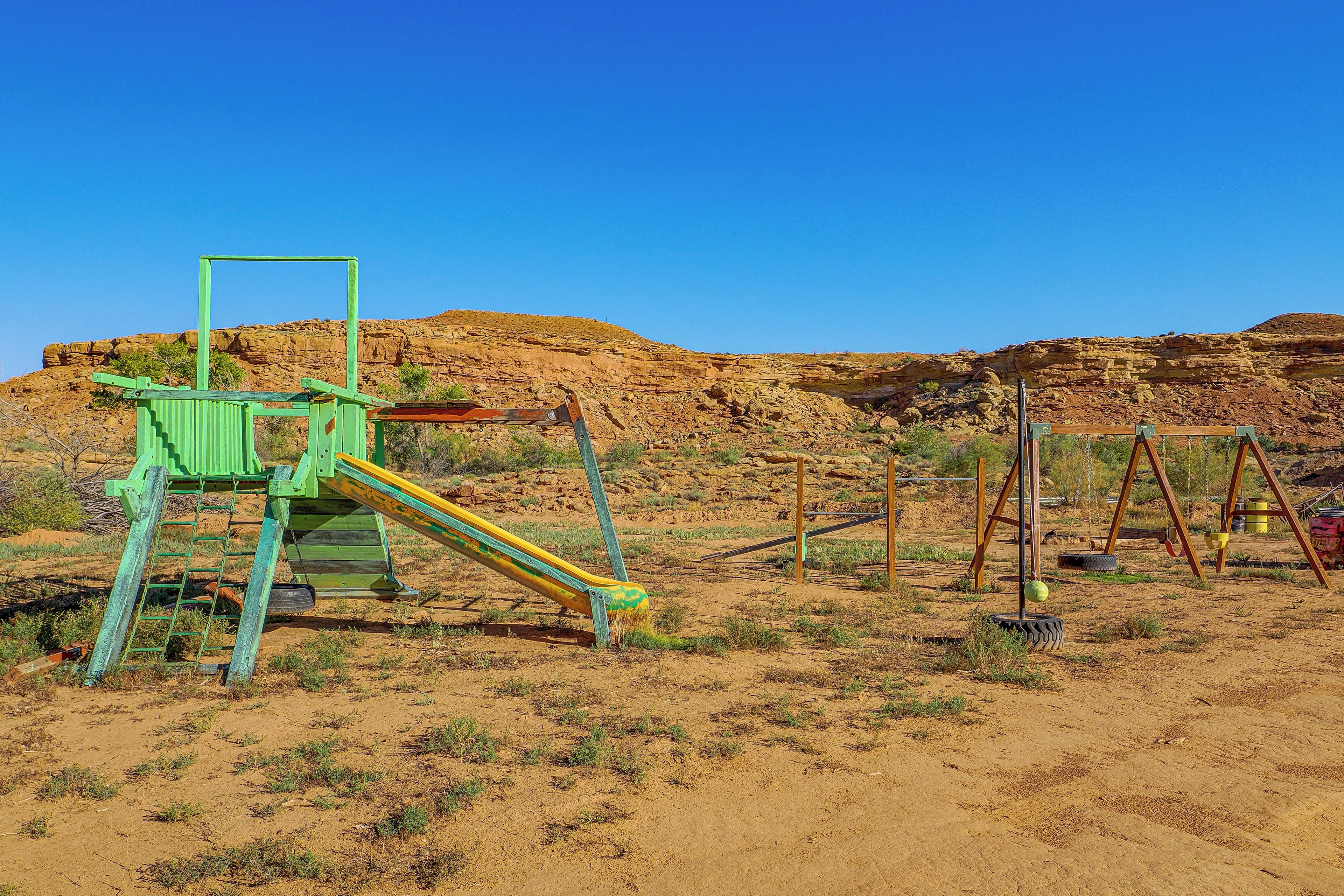 A playground with a slide and swings in a desert landscape.
