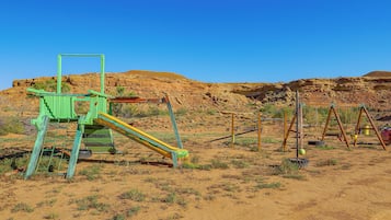 A playground with a slide and swings in a desert landscape.