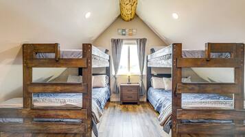 Una habitación con dos literas, una mesita de noche pequeña con lámpara y una ventana con cortinas.