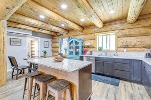 A log cabin interior with a kitchen area featuring granite countertops, bar stools, and a blue cabinet. - 'rustic Cliff Ranch' in Uintah Basin: Dogs Welcome (Fort Duchesne)