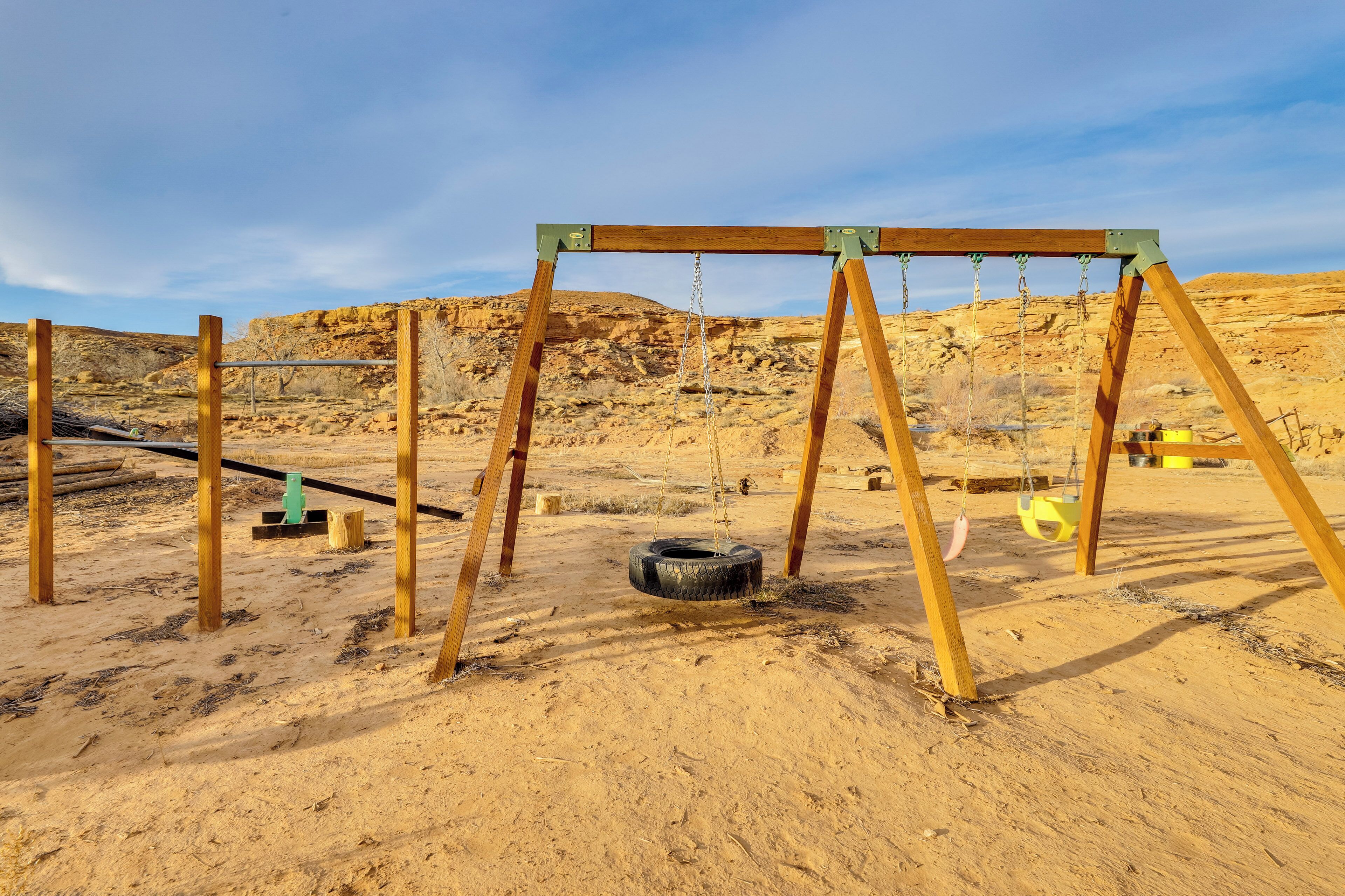 A wooden swing set in a desert with a clear sky.