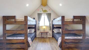Una habitación con dos literas, una mesita con lámpara y una ventana con cortinas.