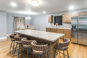 A kitchen with a central island, bar stools, wooden cabinets, and stainless steel appliances.