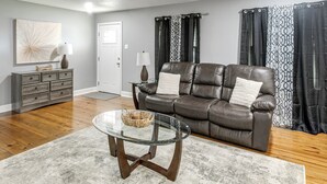 A living room with a leather sofa, glass coffee table, and a gray patterned rug.