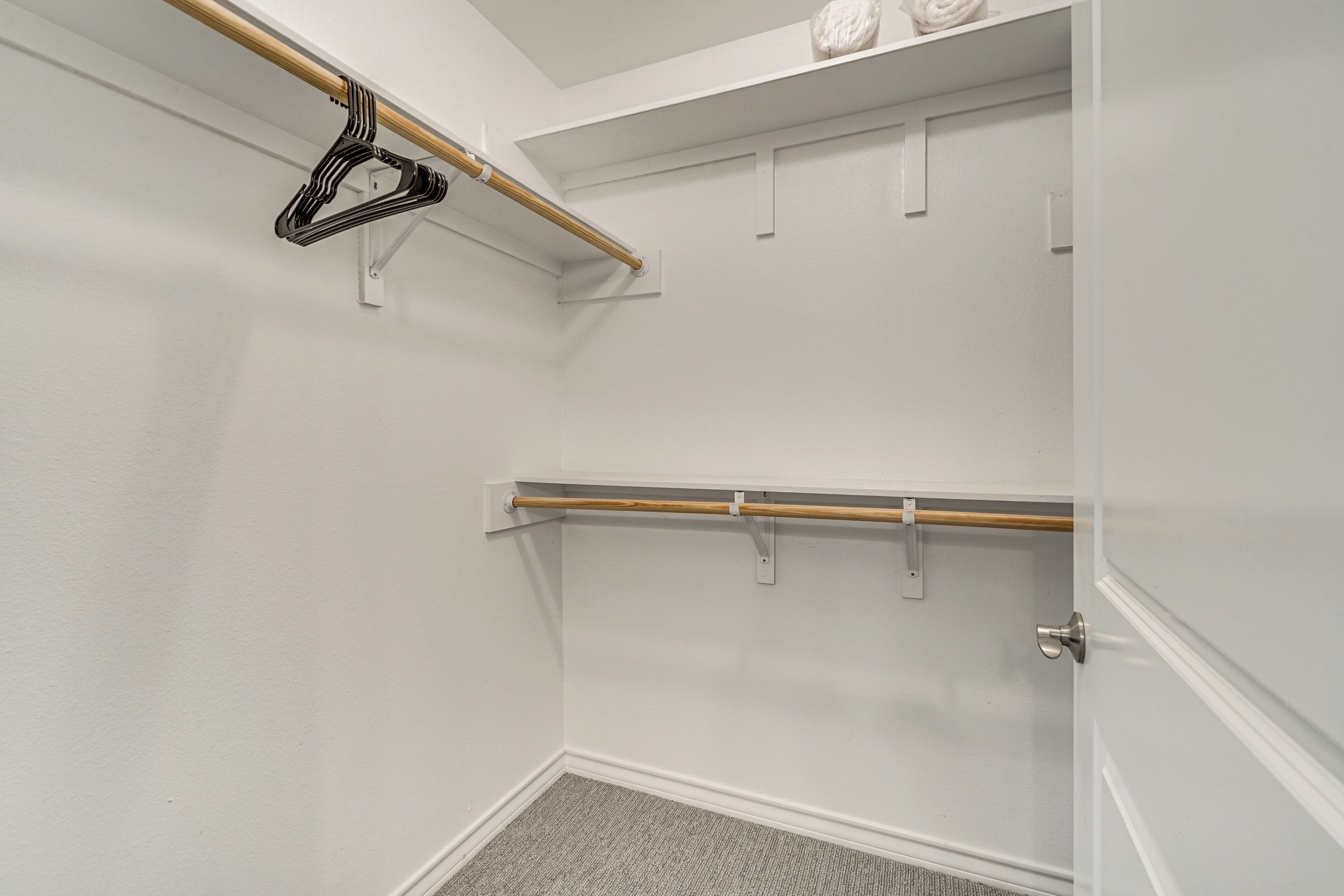 Een kast met een houten stang en een zwarte ophanger.