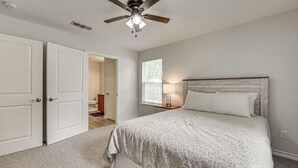 Un dormitorio con cama, ventilador de techo, ventana y puerta.