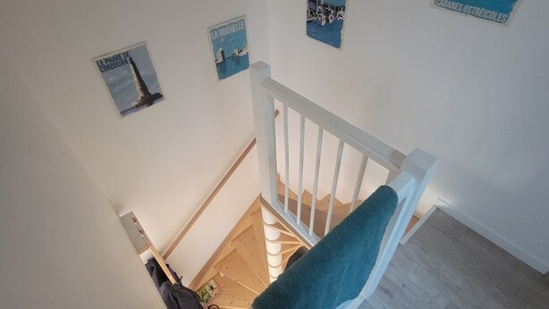 Een trap met een witte leuning, houten treden en een blauwe handdoek op de balustrade.