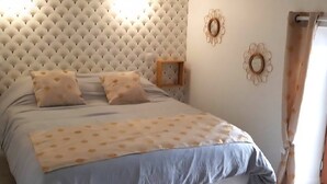 Ein Bett mit einer gebügelten Kopfteil, ein Nachttisch und blumengemälde an der Wand.