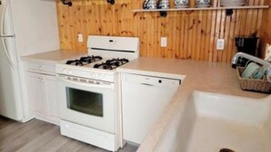 Eine Küche mit Herd, Backofen und Geschirrspüler, Holzvertäfelung und Spüle.