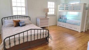 Ein Schlafzimmer mit einem Metallbettgestell, einer weißen Kommode und einem Etagenbett.