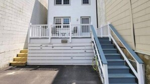 Ein schmaler Gang mit einem weißen Gebäude, das einen kleinen Balkon und eine Treppe zum Eingang hat.